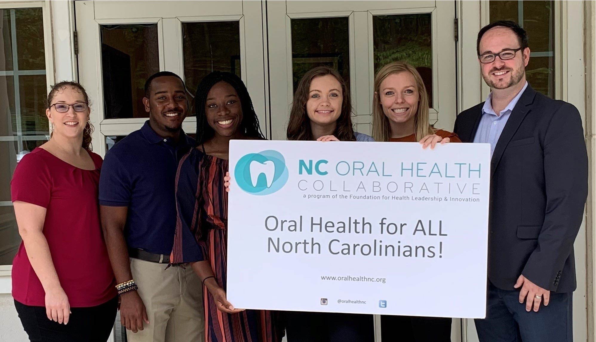 Picture with Campbell University public health students and NCOHC staff holding "Oral Health for All" sign